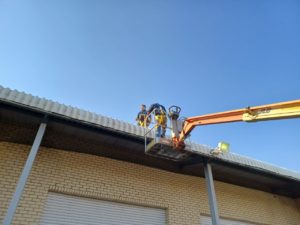 Technicians installing bird proofing netting on a high building.